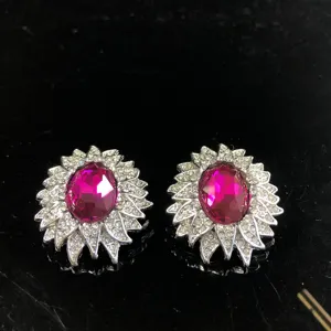 Primer plano detallado de pendientes vintage de estrás fucsia con cristales brillantes.