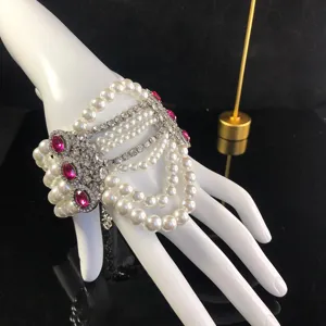 Vista detallada del brazalete de mano multicapa de perlas con cristales y pedrería rosa.