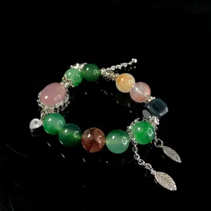 Detailed close-up of multi-gemstone beaded bracelet with elegant metal leaf charms and crystal stones.
