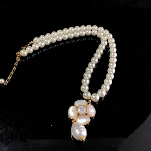 Close-up detail of double-layer pearl necklace with mother-of-pearl camellia pendant.