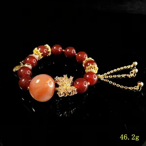 Red bead crystal bracelet detail showing golden crown charms and butterfly pendant craftsmanship.