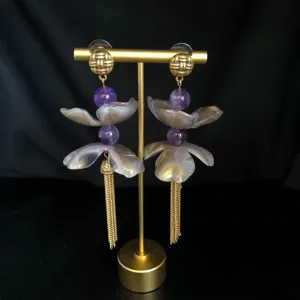 Detailed close-up of long Chinese style floral tassel earrings with purple beads and gold studs.