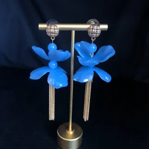 Close-up detail shot of elegant blue floral tassel earrings featuring golden metal accents.