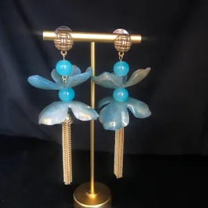 Long tassel floral earrings featuring translucent resin petals, blue beads, and gold-tone studs.