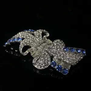 Primo piano dettaglio di spilla fiocco vintage argento con strass e cristalli blu.