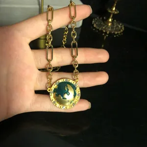 Exquisite green enamel planet pendant necklace detail view, elegant gold tone jewelry.