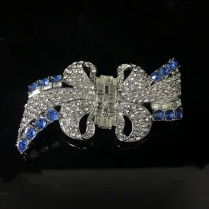 Dettaglio in primo piano della spilla fiocco vintage con strass brillanti e cristalli blu.