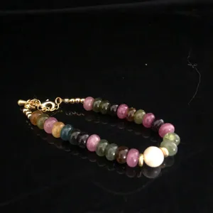 Multicolor tourmaline flat bead bracelet with white cultured pearl and gold metal clasp.