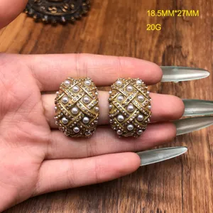 Vintage style gold pearl rhinestone earrings detail shot showing intricate design and texture.