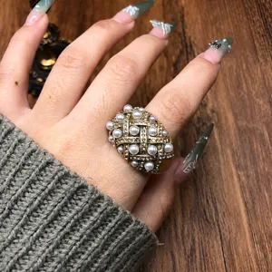 Detailed close-up of the vintage gold-toned pearl and rhinestone studded ring design.