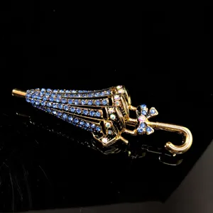 Nahaufnahme Detail der eleganten blauen Strass Regenschirm Brosche mit Goldfinish.