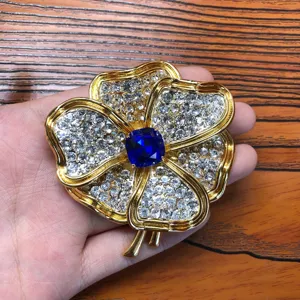 Broche fleur en strass ton or vintage avec un magnifique cristal bleu central, élégante.