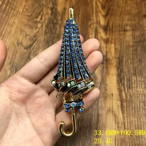 Nahaufnahme von feinen blauen Strass Regenschirm Brosche Details, goldene Legierung Accessoire.