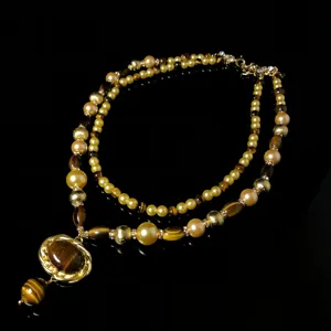 Close-up detail of multi-layered beaded necklace featuring tiger eye pendant and beads.