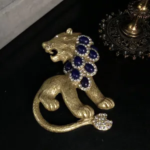 Vintage gold lion brooch with blue stones and sparkling rhinestones, exquisite detail.