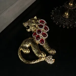Vintage gold-tone crouching lion brooch inlaid with vibrant red and clear sparkling rhinestones.
