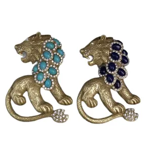 Vintage gold-tone lion brooch set featuring turquoise and blue stones with clear rhinestones.