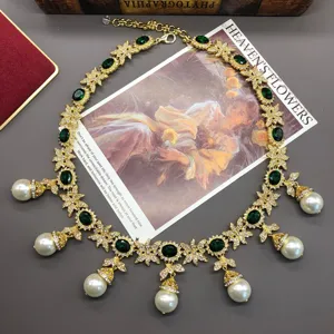Detailed view of vintage gold necklace with green stones, rhinestones and pearl tassels.