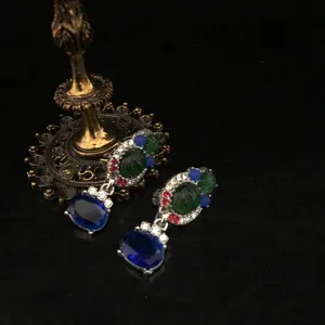 Close-up of exquisite heavy-industry rhinestone drop earrings with blue and green stones detail.
