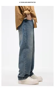 Dettaglio vista laterale di jeans in denim blu lavato ampio e casual per look streetwear.