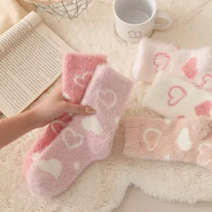 Gros plan de chaussettes d'hiver douillettes en peluche avec cœur, texture polaire douce et style.