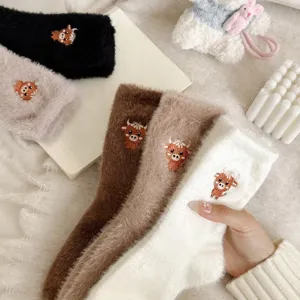 Vue détaillée de chaussettes d'hiver chaudes et duveteuses brodées de vache en peluche.