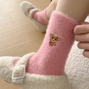 Détail de chaussettes mi-hautes rose pelucheuses avec broderie de vache de dessin animé.