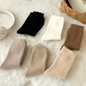Close-up of cozy plush diamond knit winter socks in assorted neutral solid colors on rug.