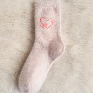 Chaussettes douillettes roses et duveteuses avec cœur rouge, parfaites pour l'hiver au chaud.