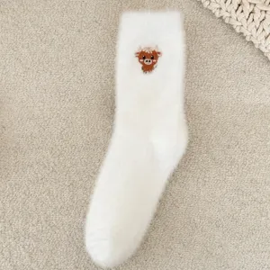 Gros plan sur des chaussettes d'hiver blanches et duveteuses avec broderie mignonne.