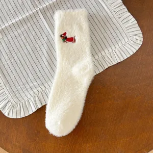 Gros plan détaillé de chaussettes moelleuses blanches d'hiver pour femme avec broderie de Noël.