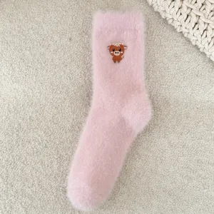 Gros plan détaillé de chaussettes douillettes roses avec broderie de petite vaches.