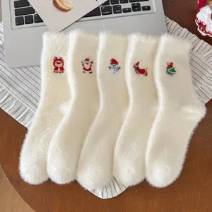 Gros plan de chaussettes blanches duveteuses brodées de motifs de Noël pour un confort douillet.