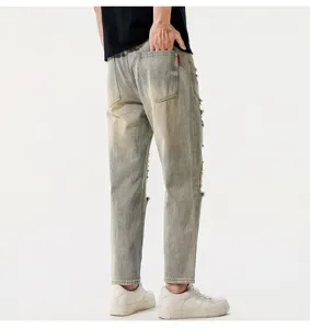 Detail view of men's vintage distressed cropped straight denim jeans in retro blue wash finish.