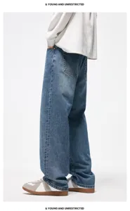 Dettaglio di jeans in denim blu scuro lavato con taglio dritto ampio stile streetwear.