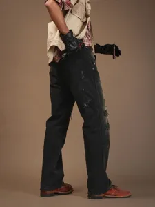 Verwitterte Graffiti-Denimhose im Streetwear-Stil mit Rissen und lockerem Schnitt.