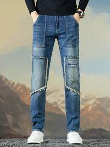 Vista detallada de vaqueros azules de hombre estilo patchwork con bolsillos y bordes deshilachados.