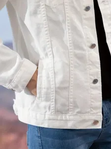 Close-up detail of a white denim jacket showing cotton fabric texture and metal buttons.