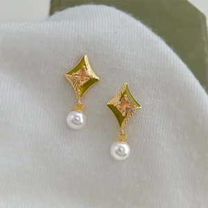 Primo piano di eleganti orecchini geometrici con smalto verde, cristallo e perla.