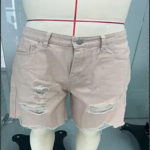 Vue détaillée du short en denim rose pour homme avec des effets usés et des franges.
