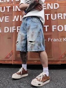 Gros plan sur un short en denim vieilli avec des éclaboussures de peinture et des genoux déchirés.