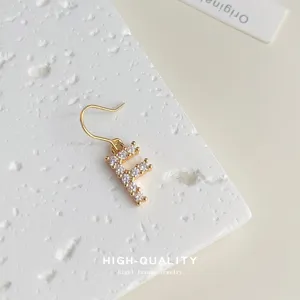 Detailaufnahme des vergoldeten Zirkonia-Ohrsrings mit Buchstabe F, elegantes Schmuckstück.