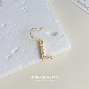 Nahaufnahme Detail der vergoldeten Zirkonia Buchstaben L Ohrringe mit feinem Glanz und Stil.
