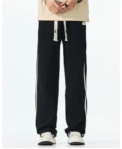 Detail view of casual sweatpants with white side stripes and drawstring waistband.