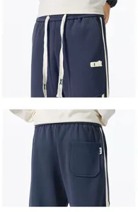 Detail view of casual loose sweatpants with side stripes, drawstrings and practical pockets.