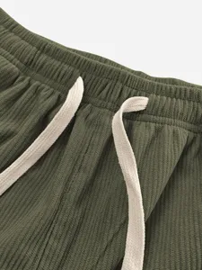 Men's casual pants elastic waistband detail with cream drawstrings and green fabric.