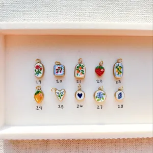 Macro view of assorted fruit and flower enamel charms with selection numbers for DIY necklaces