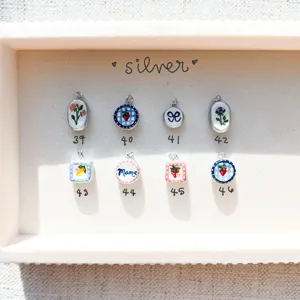 Selection of vintage ceramic charms with fruit and floral patterns in a tray