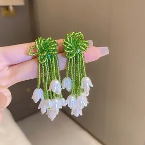 Dettaglio orecchini con nappa di perline di fiori verdi, gioielli estivi eleganti.