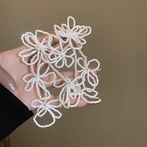 Primo piano dettagliato di orecchini con nappe di fiori di perline bianche dal design delicato.